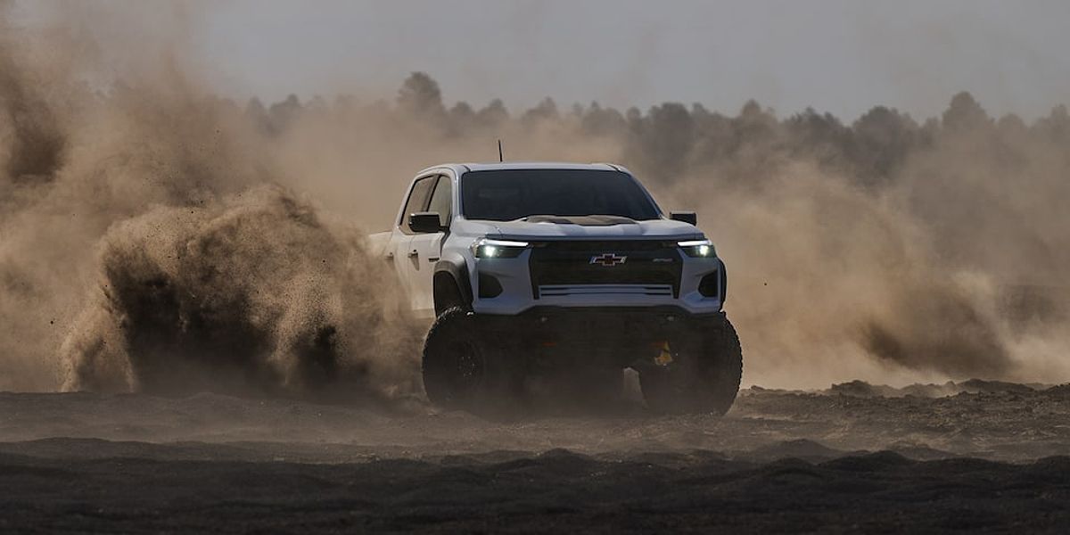 The Chevy Colorado Driving Through the Sand with a Forest in the Background